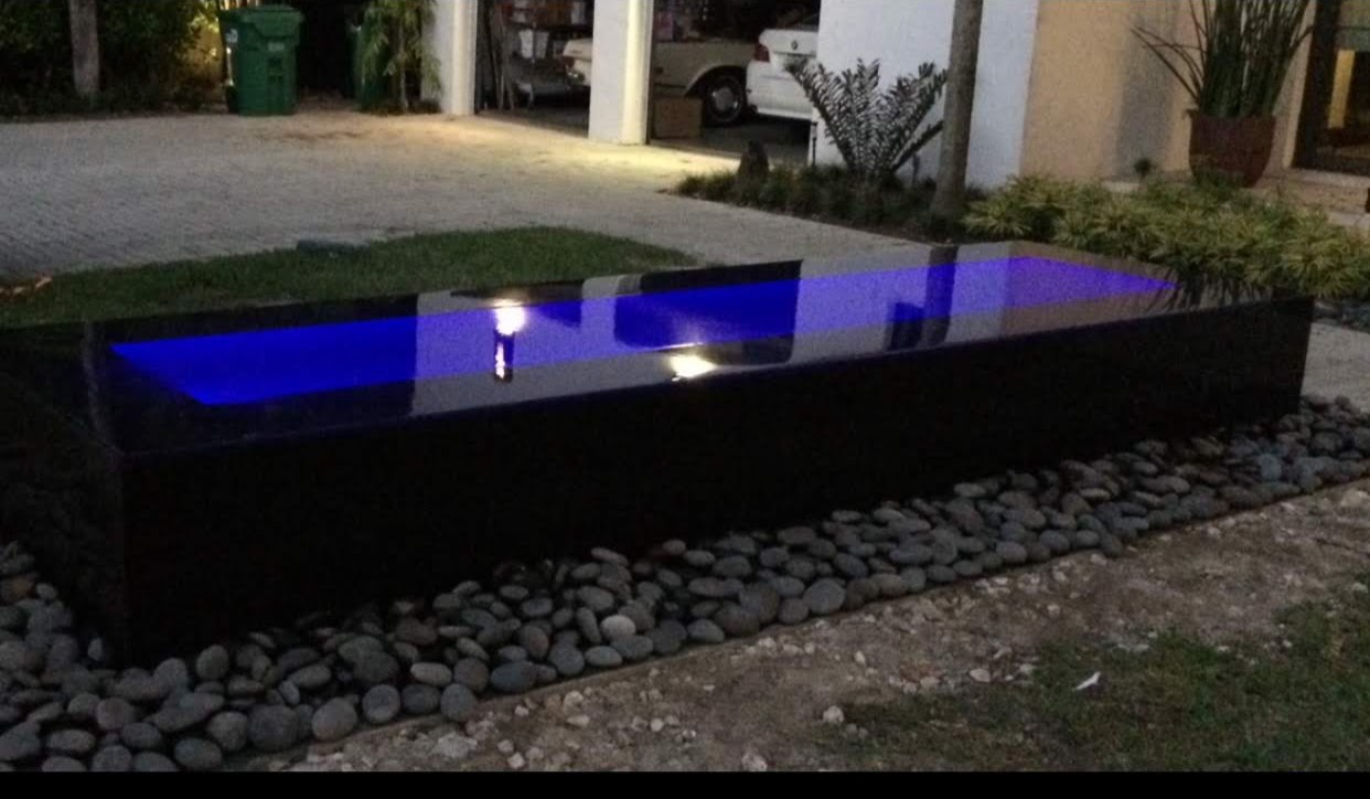 Blue-lit rectangular reflecting pool outside modern house