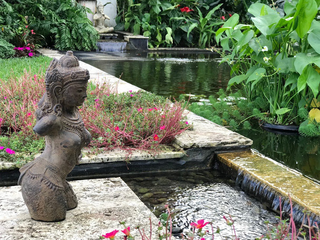 Stone goddess statue beside tranquil garden pond
